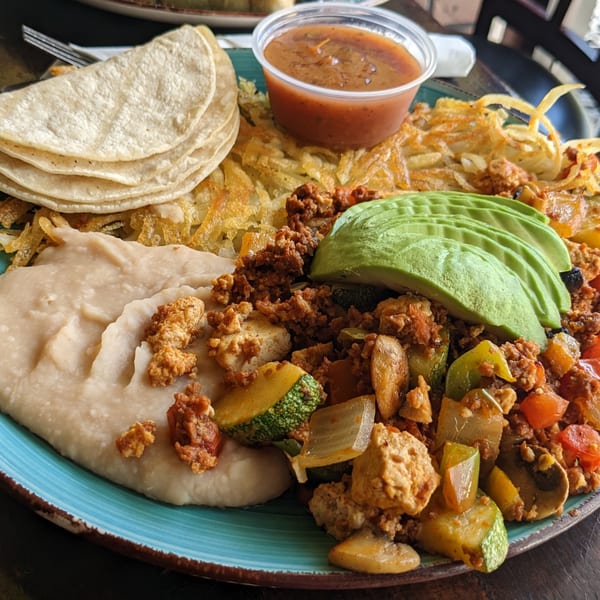 Aunt Yese's Home Cooking breakfast plate with tortillas, hash browns, refried beans, avocado, and chorizo.