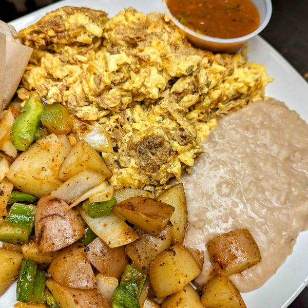 Aunt Yese's Home Cooking breakfast plate with scrambled eggs, home fries, refried beans, and salsa.
