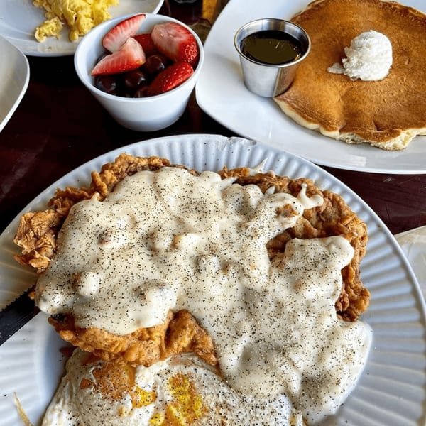 Aunt Yese's chicken fried steak with gravy, fried eggs, pancakes, and a fruit cup.