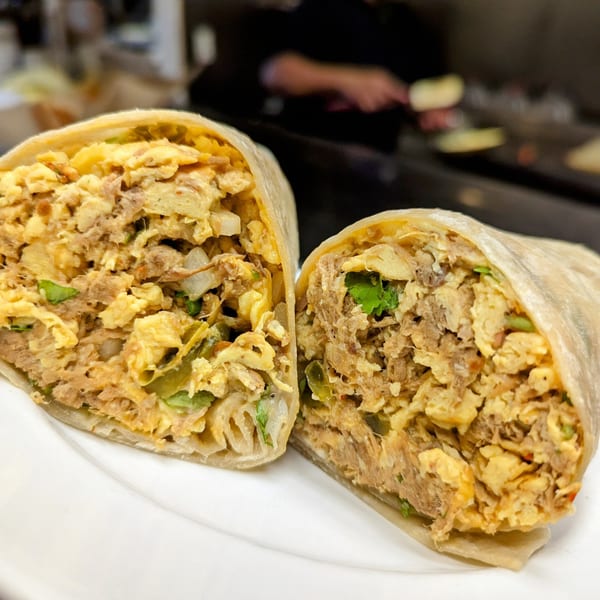 A breakfast burrito from Aunt Yese's Home Cooking, cut in half, revealing scrambled eggs and meat.